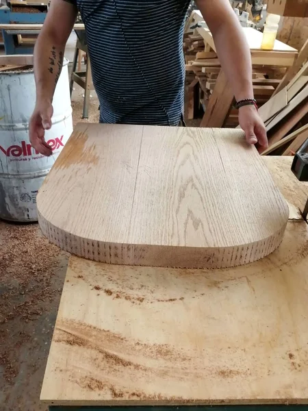 A man cuts wood on a circular saw in a joinery, A man cuts wood on a circular saw in a joinery, band saw, holding a plank, two-inch wood plank being cut, in a woodworking shop