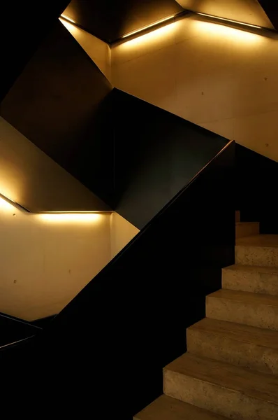 staircase of the jumex museum, with quality light and concrete, the handrail is black steel, bottom. brutalist and minimalist style.