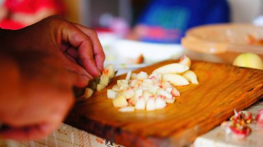old man chopping apples, for alcoholic beverage, wooden kitchen table, latin man, brown. food preparation