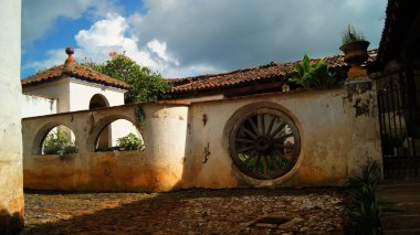 colonial architecture, arches surrounded by vegetation, play of light and shadows inside the space, natural materials, clay floor, ceiling lamp and red brick.