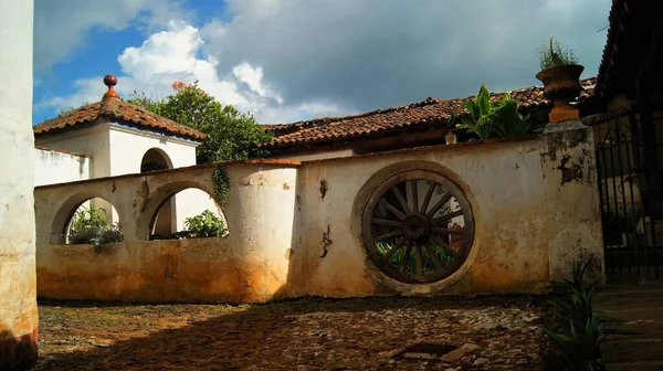 colonial architecture, arches surrounded by vegetation, play of light and shadows inside the space, natural materials, clay floor, ceiling lamp and red brick.