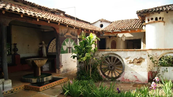 colonial architecture, arches surrounded by vegetation, play of light and shadows inside the space, natural materials, clay floor, ceiling lamp and red brick.