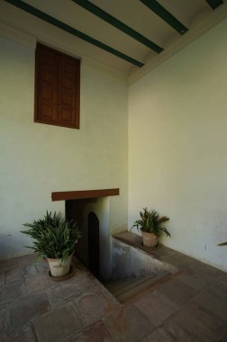 colonial architecture, arches surrounded by vegetation, play of light and shadows inside the space, natural materials, clay floor, ceiling lamp and red brick.