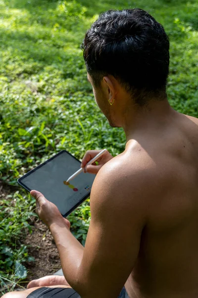 young man explaining drawing on his tablet, while teaching chakra, yoga and meditation class, mexico latin america