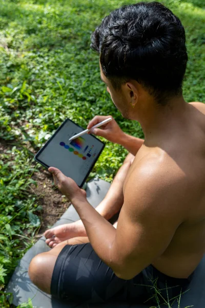 young man explaining drawing on his tablet, while teaching chakra, yoga and meditation class, mexico latin america