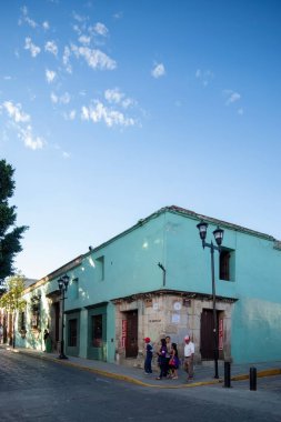 Old, abandoned building in downtown guadalajara, mexico, colonial architecture, walls with illegal graffiti, the coating is starting to fall off the walls, light poles, wires and parked cars.