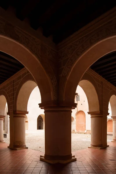 colonial architecture, arches surrounded by vegetation, play of light and shadows inside the space, natural materials, clay floor, ceiling lamp and red brick.