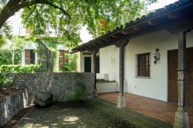 colonial architecture, arches surrounded by vegetation, play of light and shadows inside the space, natural materials, clay floor, ceiling lamp and red brick.