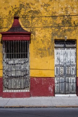 Old, abandoned building in downtown guadalajara, mexico, colonial architecture, walls with illegal graffiti, the coating is starting to fall off the walls, light poles, wires and parked cars.