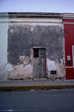 Old, abandoned building in downtown guadalajara, mexico, colonial architecture, walls with illegal graffiti, the coating is starting to fall off the walls, light poles, wires and parked cars.