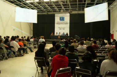 students paying attention to a lecture given by a woman, projecting about books and architectural education, students taking notes and taking pictures.
