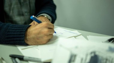 person drawing by hand with pen, pencil and ink, architectural perspectives, in color. Drawing on paper on a drawing board or desk.