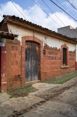 colonial architecture, arches surrounded by vegetation, play of light and shadows inside the space, natural materials, clay floor, ceiling lamp and red brick.