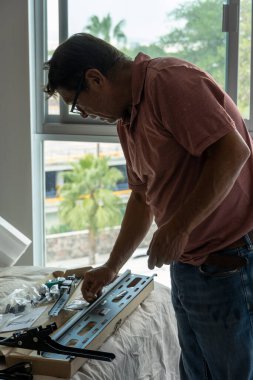 Tamirci, pencere sapını düzeltmek için tornavida kullanıyor.