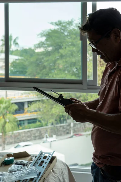 Handyman using screwdriver to fix window handle tv