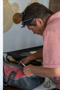 Latin adam alet çantasında aletler arıyor, İspanyol, Meksikalı, elinde tornavidayla.