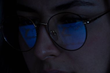 Geceleyin borsayı izleyen genç kadın, aynı pazar gözlüklerinin yansımasında da görülüyor, Meksika Latin Amerika