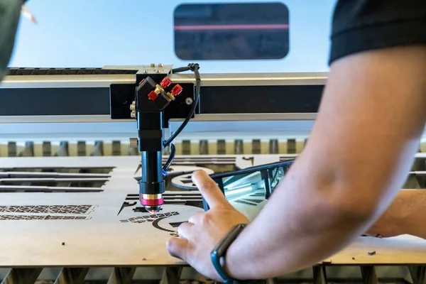 laser cutting machine, cutting wood sheets, while a man records the process, mexico latin america