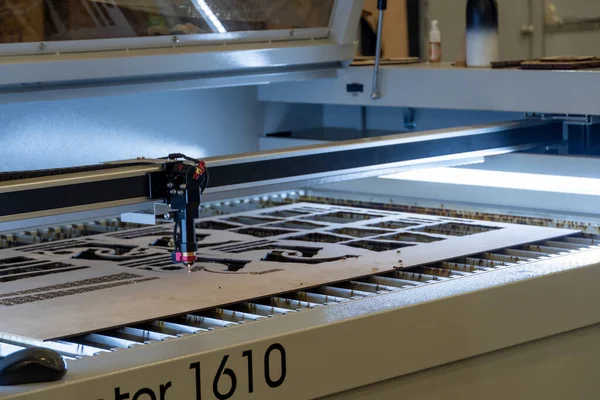 laser cutting machine, cutting wood sheets, while a man records the process, mexico latin america