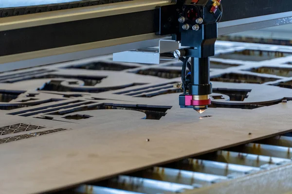 laser cutting machine, cutting wood sheets, while a man records the process, mexico latin america