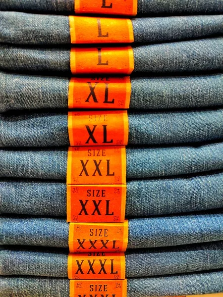 Cloth denim size trousers folded in a pile on a store window.
