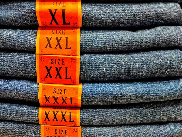 Cloth denim size trousers folded in a pile on a store window.