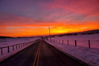 Karlı yolda kırmızı ve mor gün batımı.