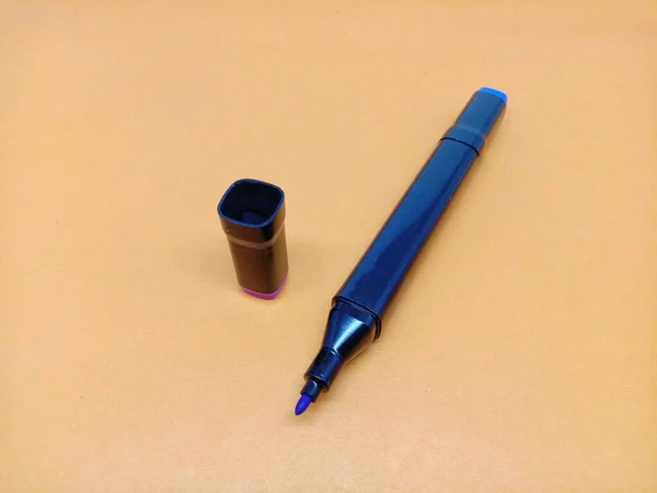 A coloring pen with open cap isolated on an orange background