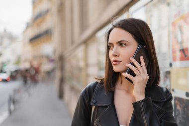 Şık ceketli esmer bir kadının portresi Paris 'te akıllı telefondan konuşuyor. 