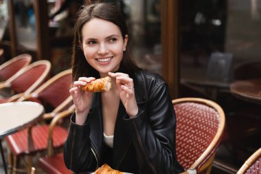 Neşeli kadın, Paris 'teki açık kafede yeni pişmiş kruvasan tutuyor. 