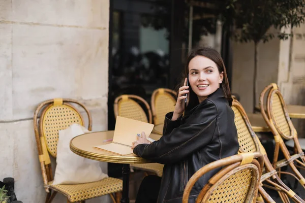 Glimlachende Vrouw Lederen Jas Praten Smartphone Zitten Outdoor Cafe Terras — Stockfoto