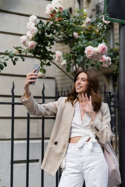 Paris 'teki şehir sokağında cep telefonuyla video görüşmesi yapan neşeli turist. 