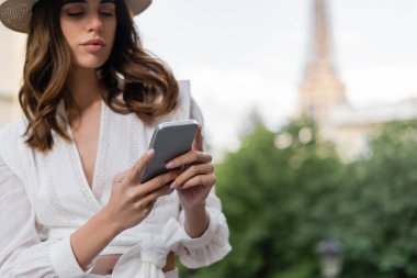 Paris 'te şehir sokağında akıllı telefon kullanan şık bir genç kadın. 