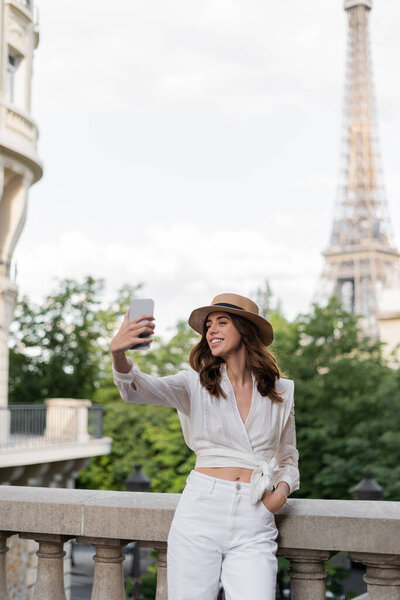 Smiling tourist taking selfie with Eiffel tower at background in Paris 