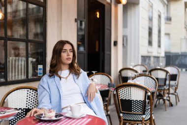 Tarz sahibi bir kadın Paris 'teki kafe terasında tatlı ve kahvenin yanında otururken gözlerini kaçırıyor. 