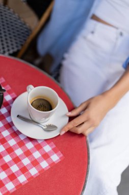 Paris 'teki kafe terasında bir fincan kahvenin yanında oturan kadın manzarası. 