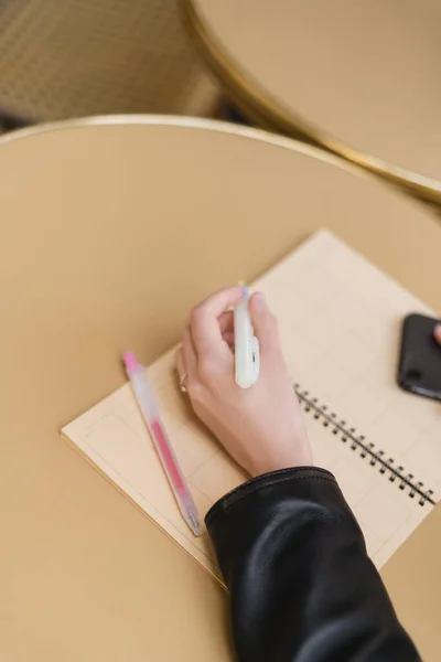 Cropped view of woman holding marker pen near blank notebook on round table — Stock Photo