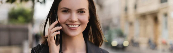 Портрет щасливої жінки в чорній шкіряній куртці, що говорить на смартфоні на вулиці в Парижі, банер — стокове фото