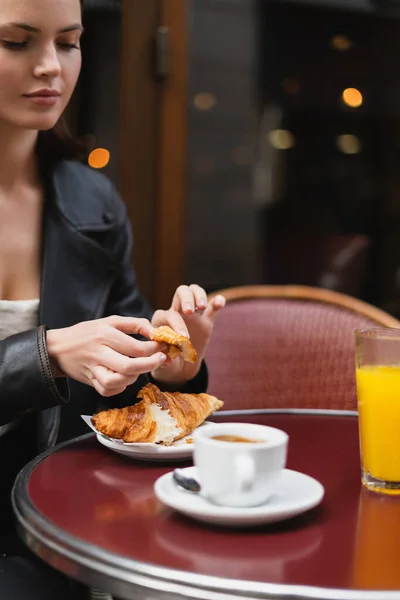 Donna che tiene croissant vicino a tazza di caffè e vetro di succo d'arancia in caffè all'aperto a Parigi — Foto stock