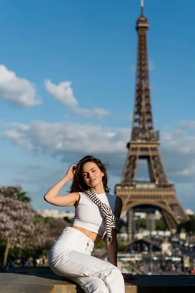 Pretty young woman in stylish outfit sitting near eiffel tower in paris, france — Stock Photo