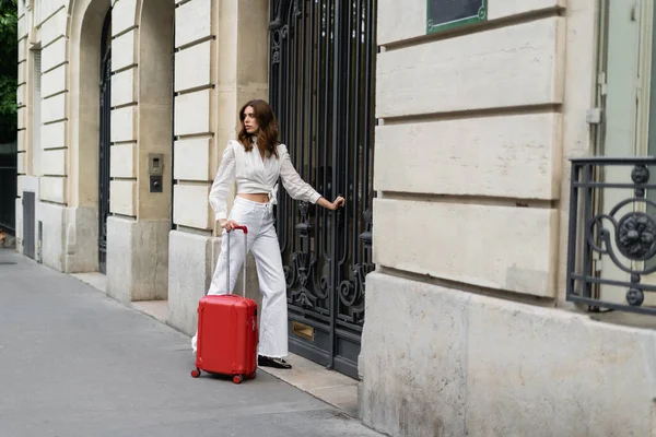Mulher elegante com mala em pé perto do edifício na rua urbana em Paris — Fotografia de Stock