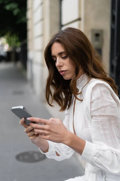 Турист у блузці користується мобільним телефоном на міській вулиці в Парижі. — стокове фото