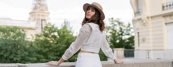 Trendy woman in sun hat looking at camera with Eiffel tower at background in France, banner — Stock Photo