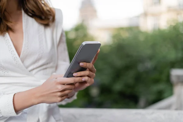 Vista ritagliata di donna alla moda utilizzando smartphone in strada a Parigi — Foto stock