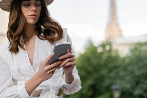 Jeune femme élégante utilisant un smartphone dans la rue urbaine de Paris — Photo de stock