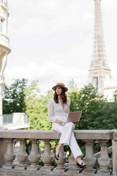 Stylish freelancer holding laptop on urban street with Eiffel tower at background in France — Stock Photo