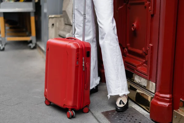 Vista recortada de la maleta cerca del viajero en la calle urbana de París - foto de stock