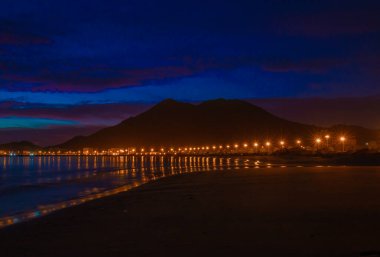 Twilight view of Khorfakkan beach with warm light and its reflection