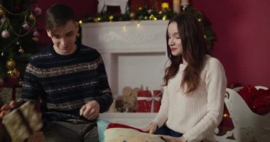 Genç bir çift Noel ağacı ve şöminenin önünde öpüşüp kucaklaşmayı sunuyor. Yeni Yıl