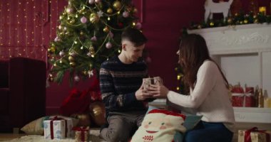 Genç bir çift birbirlerine hediye veriyor ve Noel ağacının önünde sarılıyorlar. Yeni Yıl